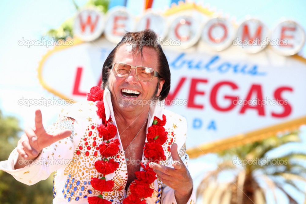 Las Vegas Elvis impersonator laughing having fun in front of Welcome to Fabulous Las Vegas sign.
