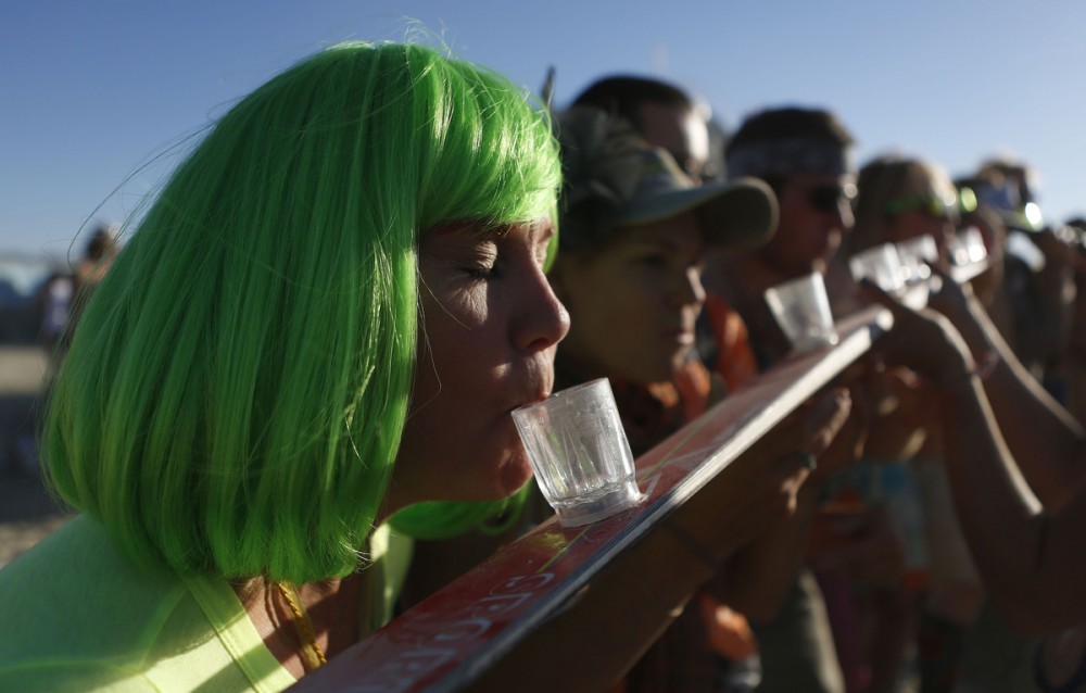 A woman of the playa name "Indigo" participates in a drinking game during the Burning Man 2012 "Fertility 2.0" arts and music festival in the Black Rock Desert of Nevada