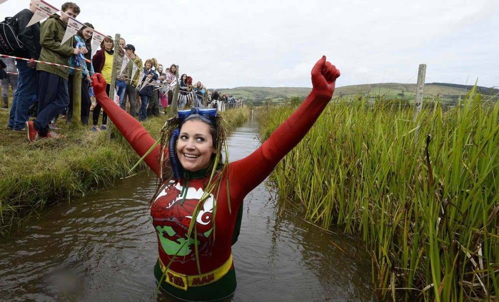 Joanna Parker celebrates finishing in the World Bog Snorkelling Championships at Waen Rhydd bog on the outskirts of LLanwrtyd Wells, Powys, Wales August 24, 2014. The annual event, where competitors swim in a marshy trench with flippers and a snorkel, brings together participants from all over the world, including France, Germany, Australia, New Zealand, the U.S. and Canada. REUTERS/Rebecca Naden (BRITAIN - Tags: SOCIETY TPX IMAGES OF THE DAY) ORG XMIT: RLN11