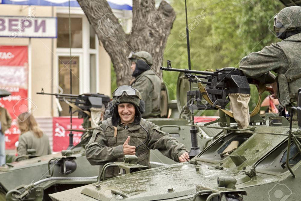 VOLGOGRAD - MAY 9: Happy Russian soldier in the background of a column of armored vehicles built for the victory parade. May 9, 2015 in Volgograd, Russia.